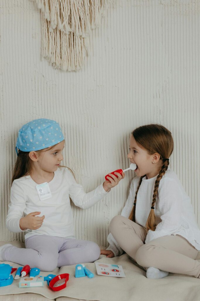 Two little girls sitting on a blanket with toothbrushes