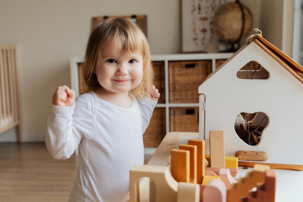 Adorable toddler joyfully playing with toys in a cozy indoor playroom, enjoying fun and happiness.